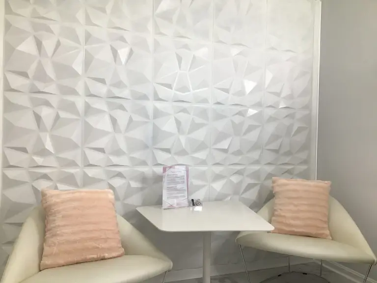 Waiting area with blush cushions and a sculpted white feature wall